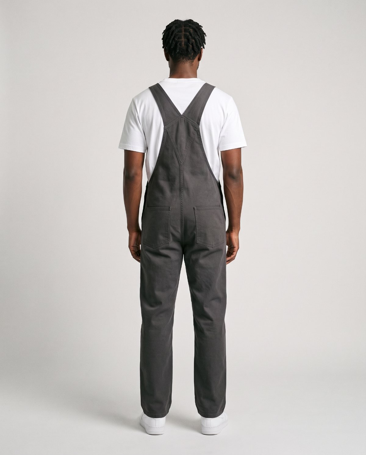 Back view of a man in charcoal bib overalls with straps crossed flat across the upper back and a smooth seat